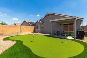 Une maison dotée d’un patio, d’un espace extérieur aménagé et couvert, et d’une petite pelouse.