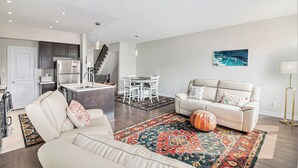Un salon moderne avec un canapé, une table basse et un tapis. Il y a également un coin cuisine avec un réfrigérateur et une table à manger avec des chaises.