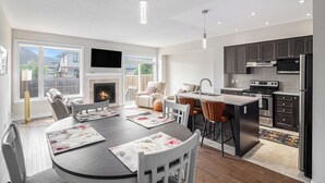 Une cuisine moderne avec des meubles de couleur sombre, des appareils en acier inoxydable et un îlot central.