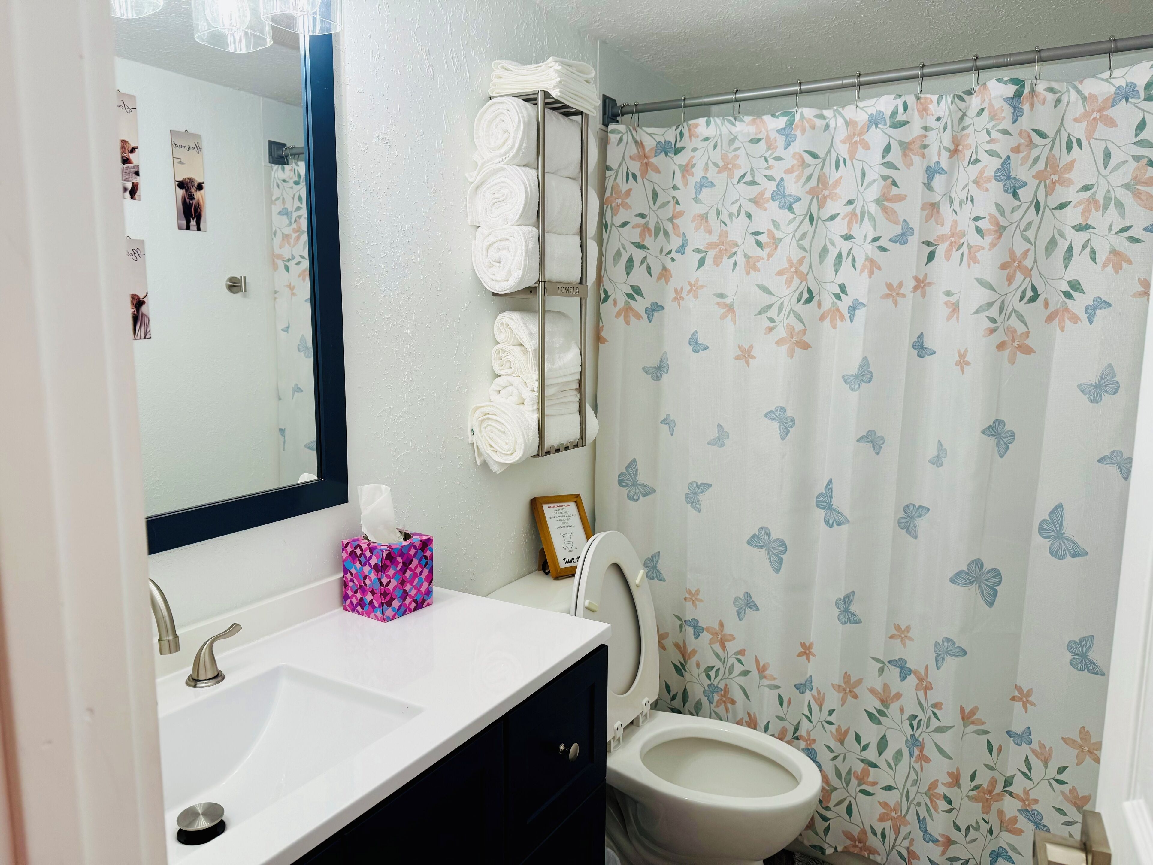 A bathroom with a white sink, a toilet, a mirror, and a shower curtain with a floral pattern.