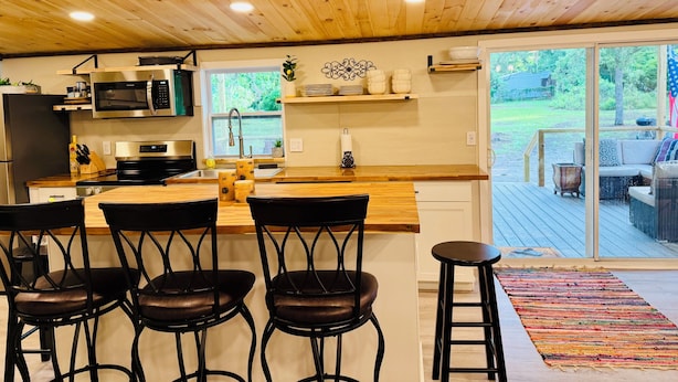 Une cuisine moderne avec un plafond en bois, des appareils électroménagers en acier inoxydable et une grande fenêtre.