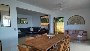 A spacious living area with a large wooden dining table, two sofas, and a ceiling fan. - An unusual haven of peace overlooking the turquoise lagoon of Haapiti in Moorea (Moorea-Maiao)