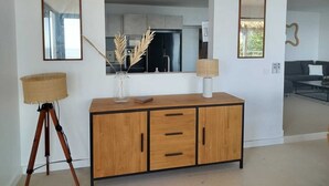 A modern living room with a wooden cabinet, a tripod lamp, and a mirror. - An unusual haven of peace overlooking the turquoise lagoon of Haapiti in Moorea (Moorea-Maiao)
