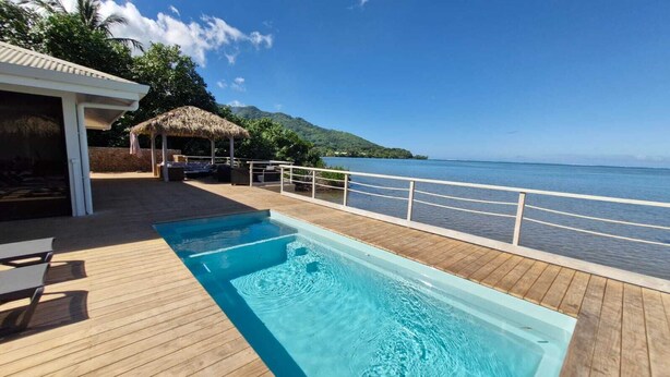 A wooden deck with a pool, a thatched-roof structure, and a view of the sea. - An unusual haven of peace overlooking the turquoise lagoon of Haapiti in Moorea (Moorea-Maiao)