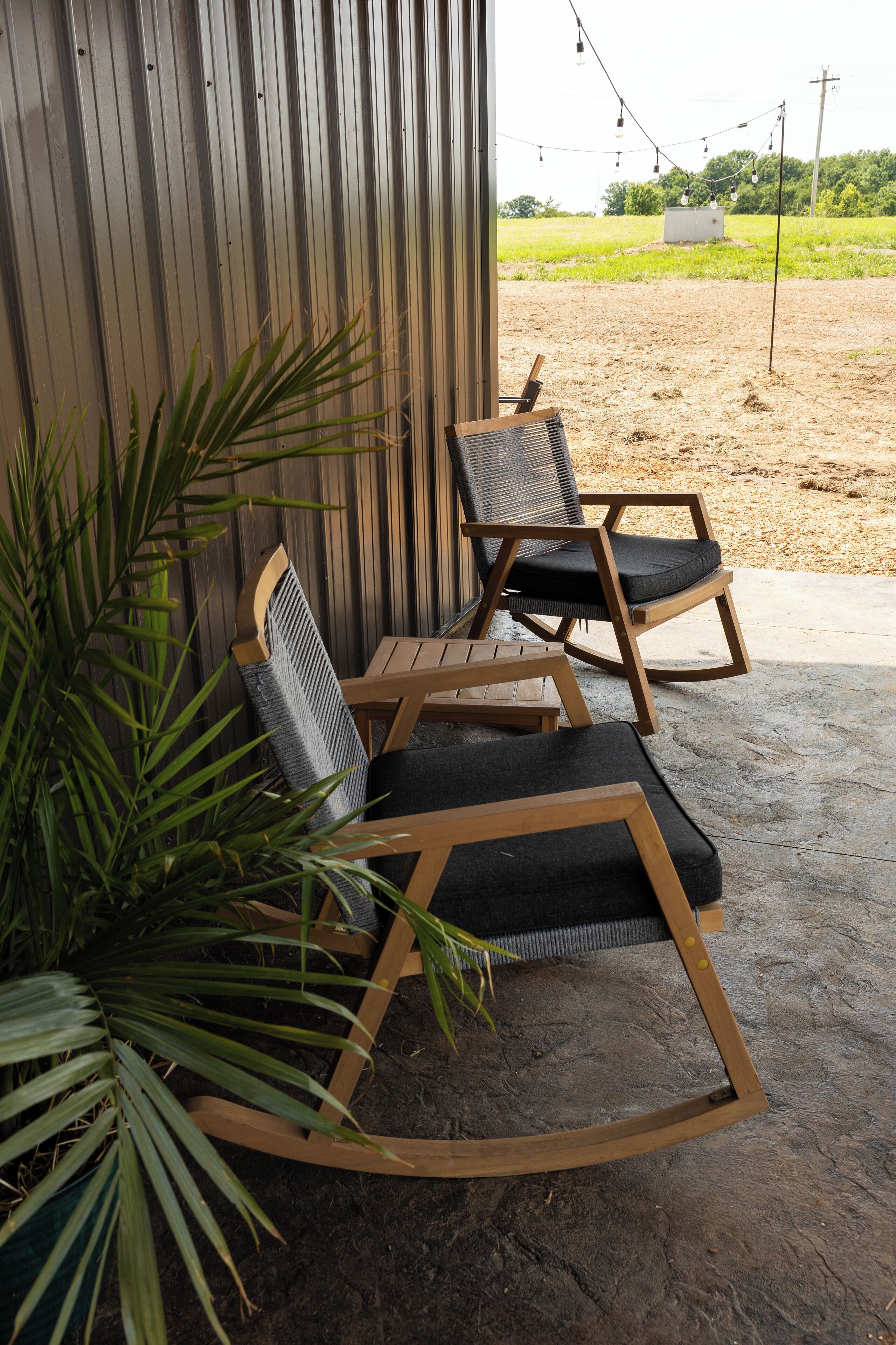 A patio area with two rocking chairs and a potted plant.