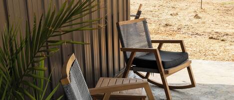 A patio area with two rocking chairs and a potted plant.