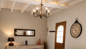 Ein Wohnzimmer mit einem gelben Ledersofa, einem Holztisch, einer Kronleuchter, einer Uhr und einem Sideboard.