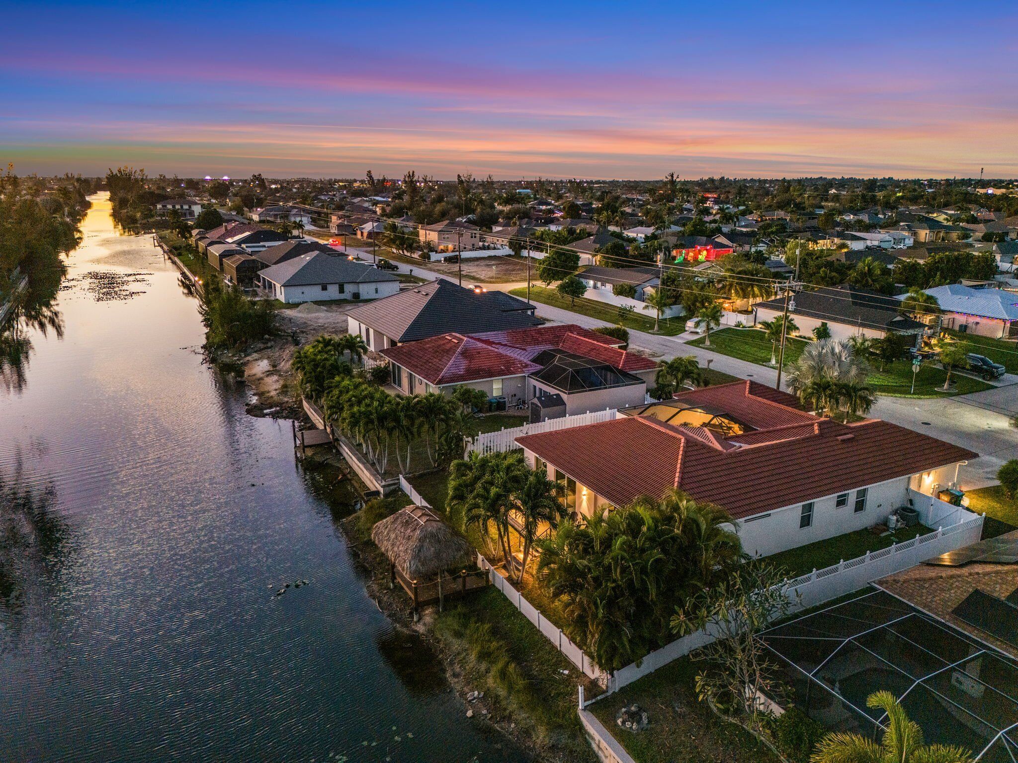 Zona residencial con casas a lo largo de un río, que presenta una combinación de edificios de uno y varios pisos, algunos con tejados rojos y otros con grises.