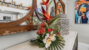Une cuisine moderne agrémentée d’un grand miroir, d’une composition florale décorative et d’un tableau contemporain accroché au mur.
