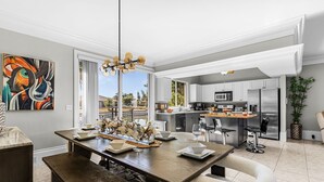 Une cuisine moderne dotée d’appareils électroménagers en acier inoxydable, un coin repas avec une table et des chaises en bois, et une grande fenêtre offrant une vue sur l’extérieur.