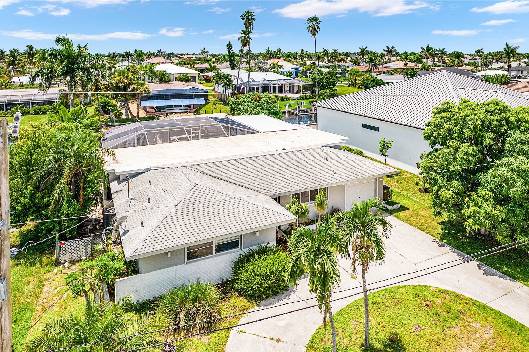 A residential area with houses, palm trees, and a clear sky.