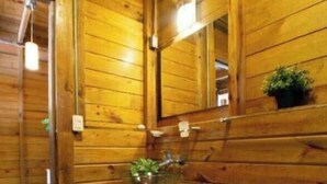 Ein Badezimmer aus Holz mit Toilette, Waschbecken und Spiegel.