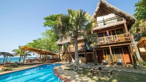Ein Resort mit Pool, strohgedeckten Gebäuden und Palmen.