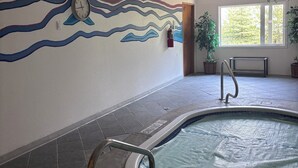En inomhuspool med ett kaklat golv, en väggmålning och en klocka.