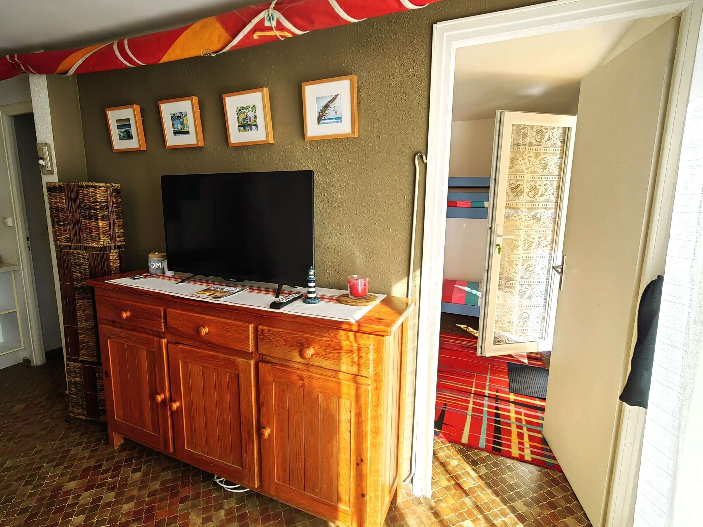 Une pièce avec un meuble en bois, un téléviseur à écran plat et des tableaux encadrés accrochés au mur.