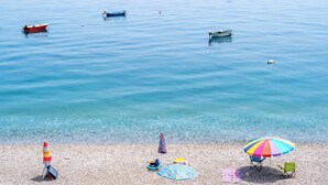 A beach with several boats on the water, clear shallow water, and beach umbrellas and chairs. - Casa Serafina - Sinfonia (Letojanni)