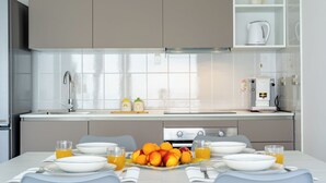 Una cocina moderna con una mesa de desayuno lista, que incluye frutas y bebidas.