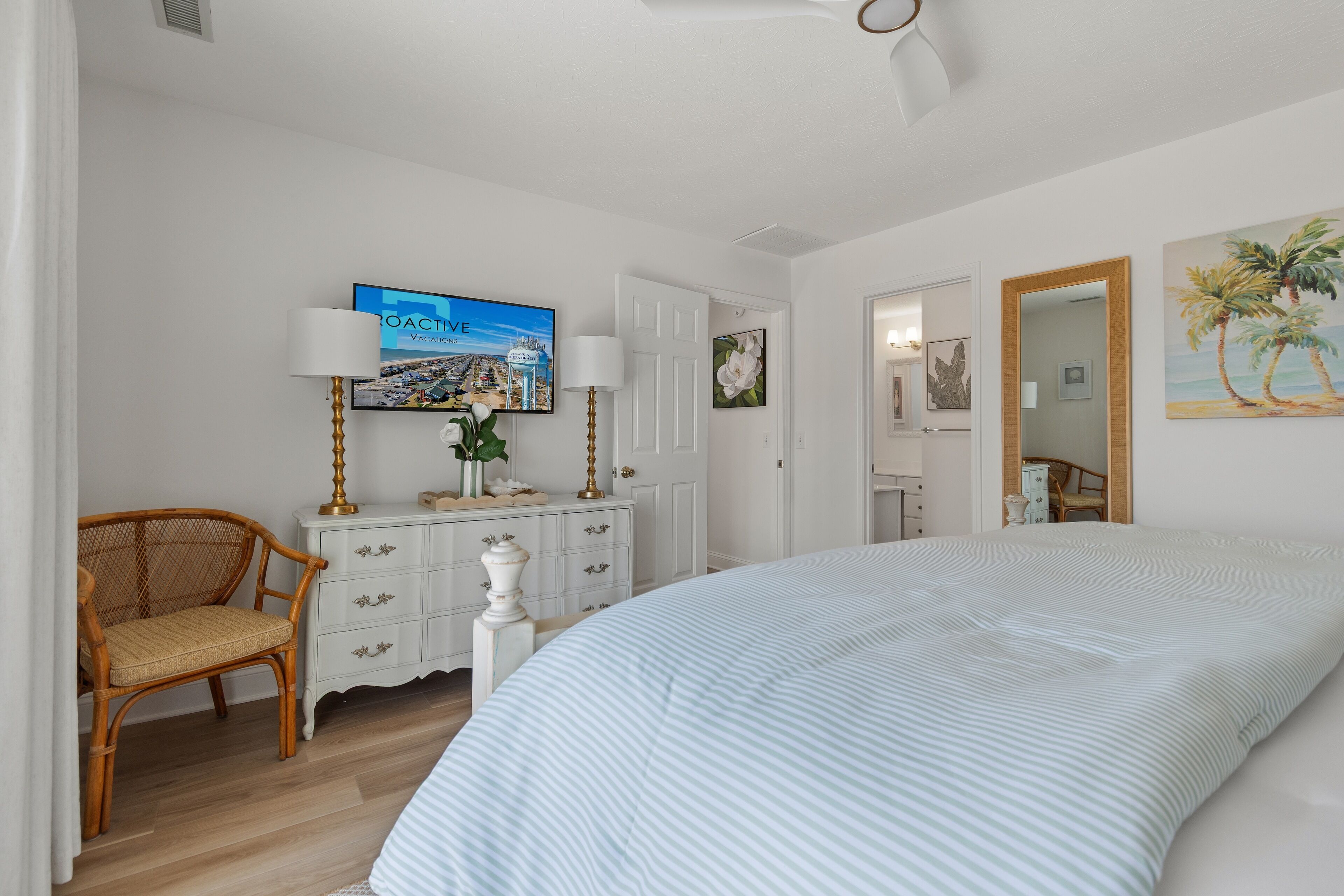Een slaapkamer met een groot bed, een televisie aan de muur, een dressoir en een stoel.