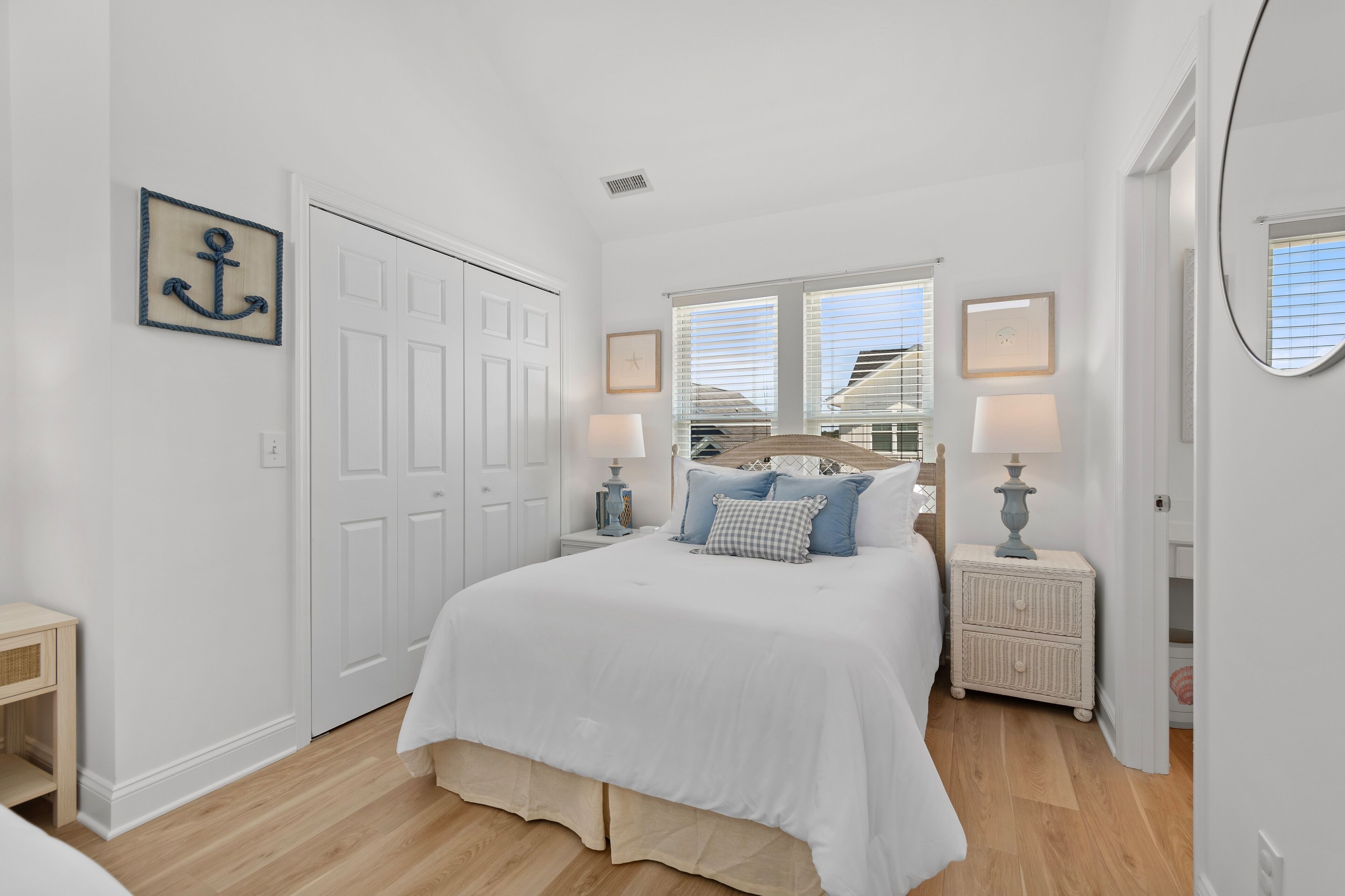 A bedroom with a large bed, two bedside tables with lamps, a wardrobe, and a window with blinds.