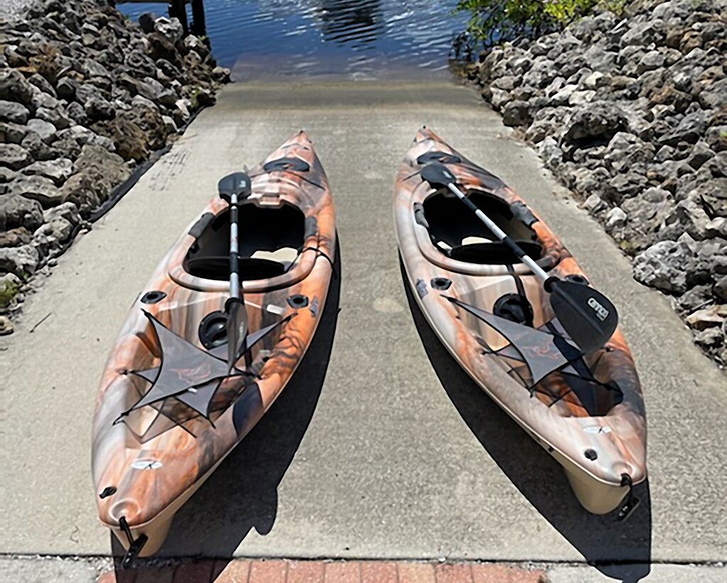 Deux kayaks sont garés sur un chemin de béton, au bord d’une côte rocheuse.