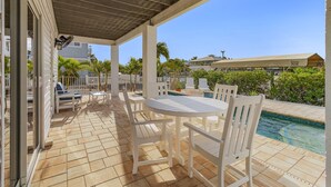 A covered patio with a pool, white furniture, and a view of the surrounding area. - Beautiful 3/3 Island Retreat with Heated Pool, Dock & Private Boat Ramp. (Bokeelia)