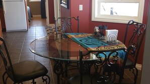 Un coin repas avec une table en verre, des chaises noires et un chemin de table à motifs.
