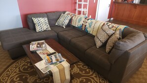 Un salon avec un canapé d’angle, une table basse et un tapis à motifs.
