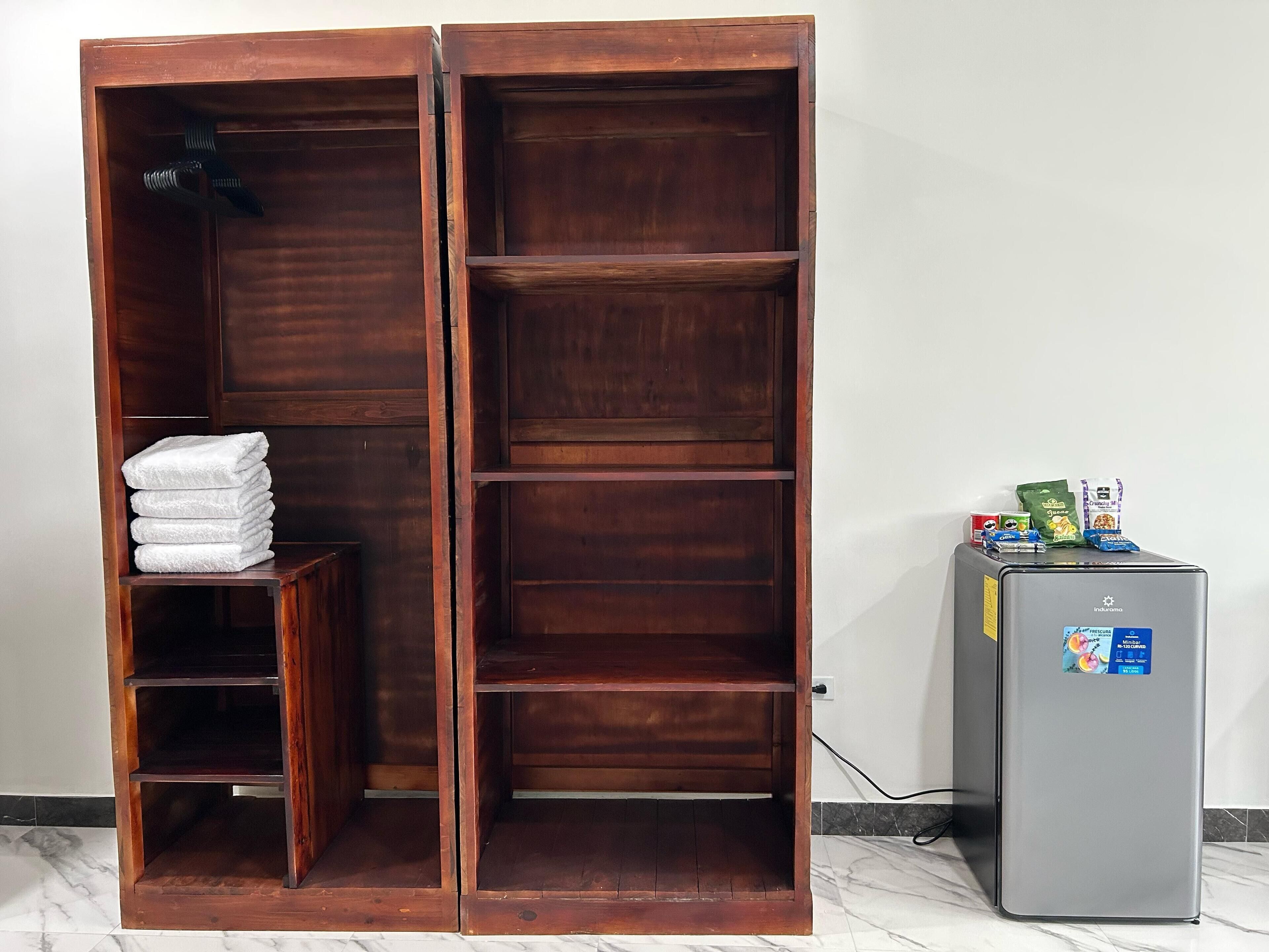 Ein Kleiderschrank mit mehreren Regalen und ein kleiner Tisch mit gefalteten Handtüchern.