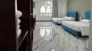 A hotel room with two beds, marble flooring, a wooden wardrobe, and a window with a decorative design. - Hotel Palace (Independencia)