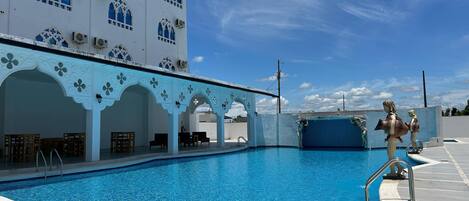 Una piscina con un cielo azul despejado al fondo.