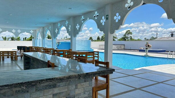 A poolside area with a stone bar, wooden seating, and decorative arches. - Hotel Palace (Independencia)