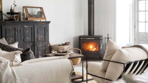 Una sala de estar acogedora con chimenea, un aparador de madera oscura y un sofá cómodo.