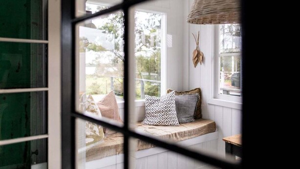Una habitación con asiento junto a la ventana, lámpara de fibra y vistas al exterior.