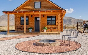 A wooden cabin with a porch, a fire pit, and outdoor seating. - Diamond Creek Cabin- New Cabin, Pet Friendly, Mountain Views (Cody)