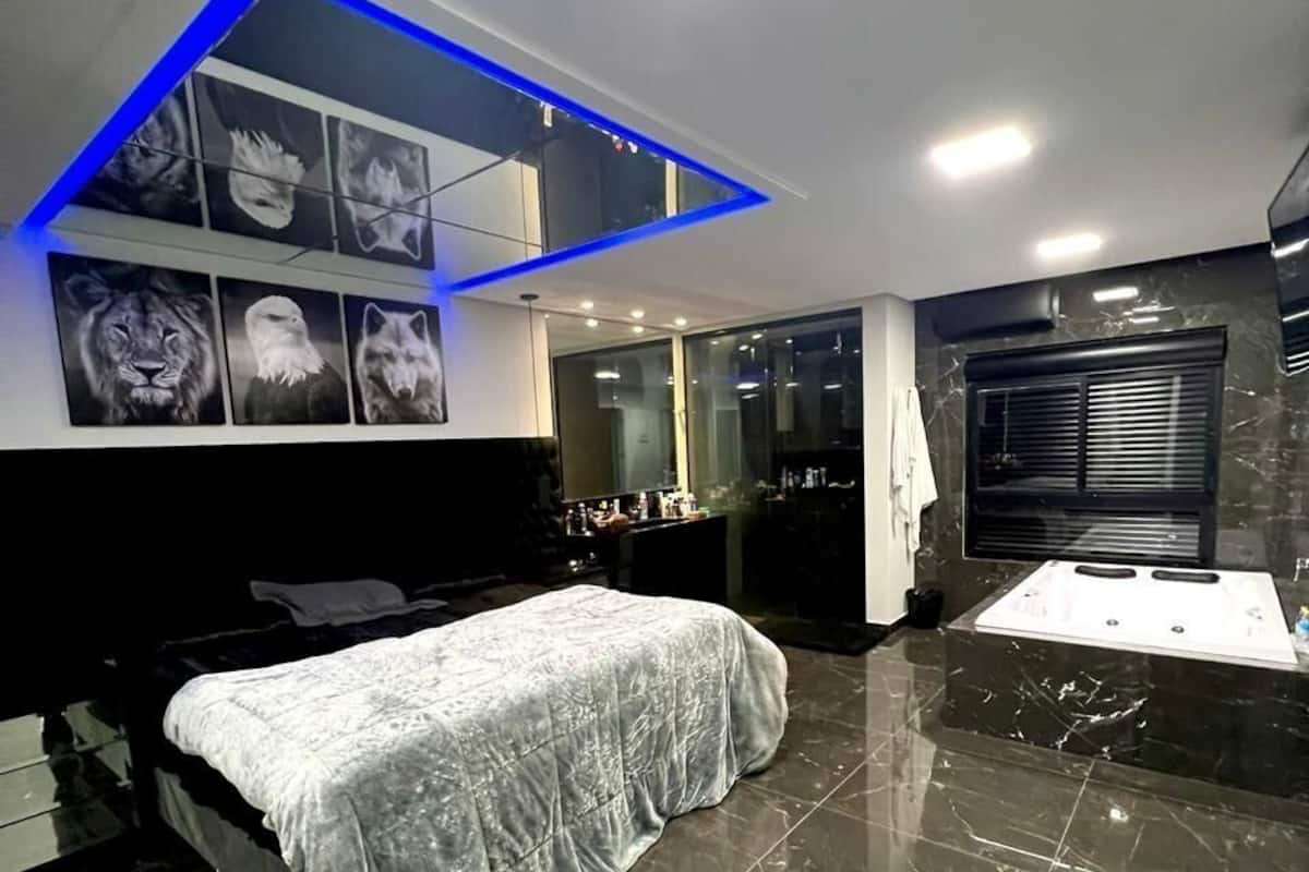 Un dormitorio moderno con cama, tocador y baño con bañera.