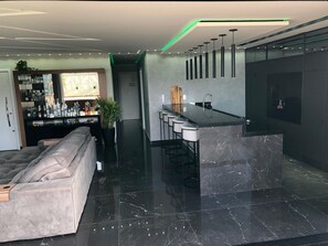Una cocina moderna con encimera de mármol, taburetes de bar y un refrigerador empotrado.