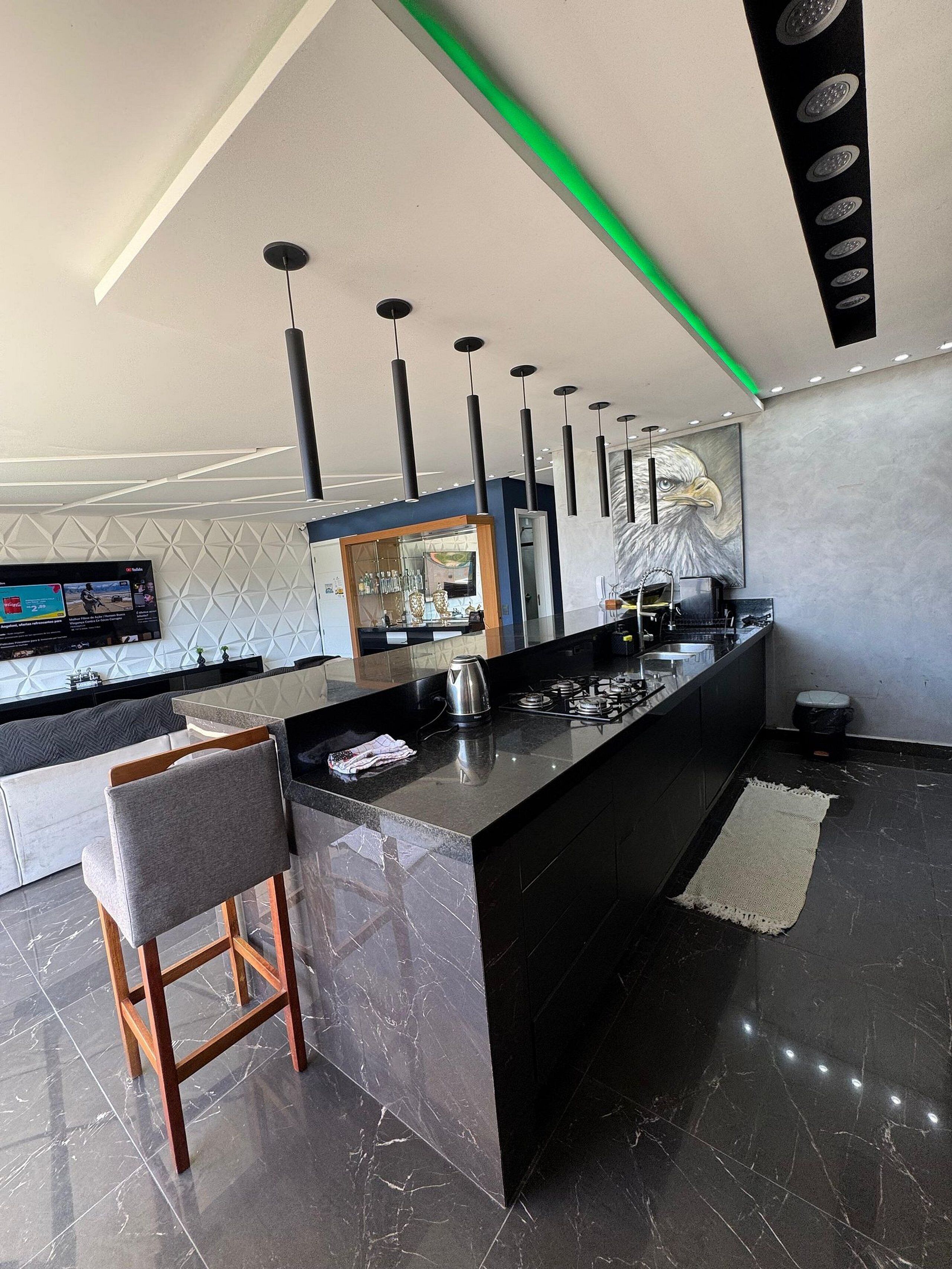Una cucina moderna con isola centrale, piani di lavoro neri e schienale in marmo.