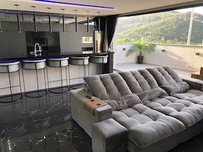 Una sala de estar moderna con un sofá gris, una mesa de centro y una zona de bar con taburetes.