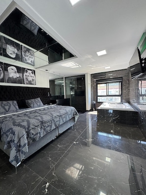 Un dormitorio moderno con una cama grande, televisión integrada y un baño con bañera.