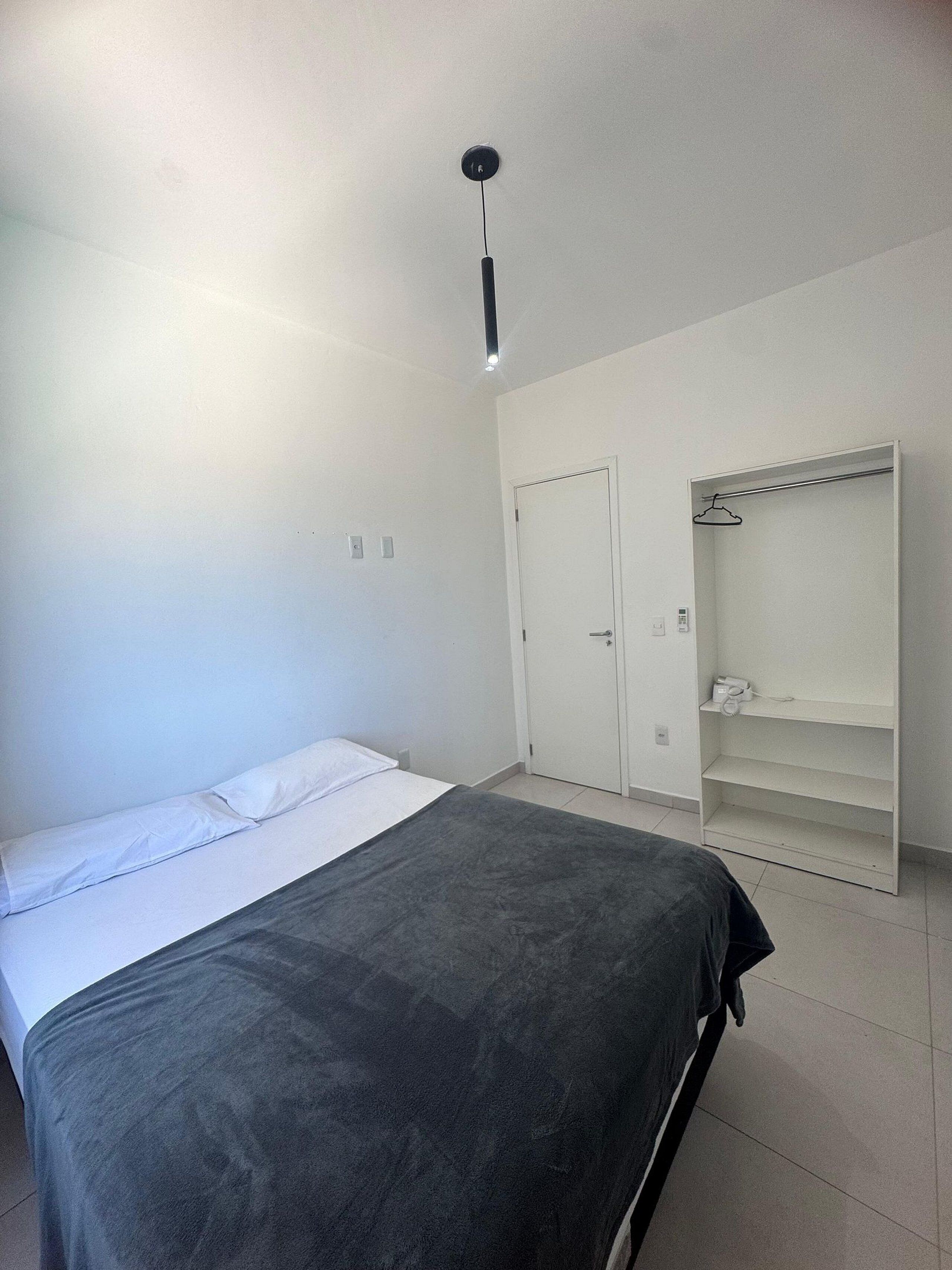 Un dormitorio con cama, armario y estante colgante.