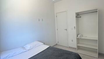 Un dormitorio con cama, armario y estante colgante.