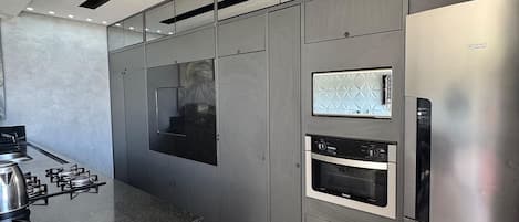 Une cuisine moderne dotée d’appareils électroménagers en acier inoxydable, d’un plan de travail en marbre et d’un four encastré.