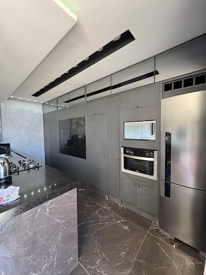 A modern kitchen with stainless steel appliances, a marble countertop, and a built-in oven. - Residencial Beach Palace (Florianopolis)