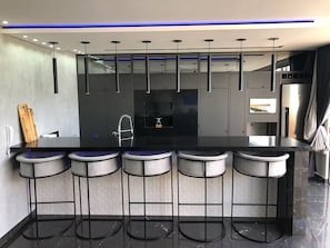 Una cocina moderna con una isla central, taburetes de bar y un televisor integrado.