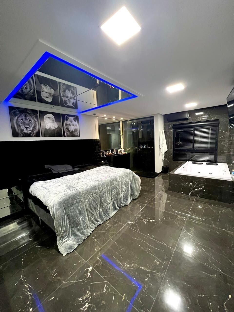 Un dormitorio moderno con cama, tocador y baño con bañera.