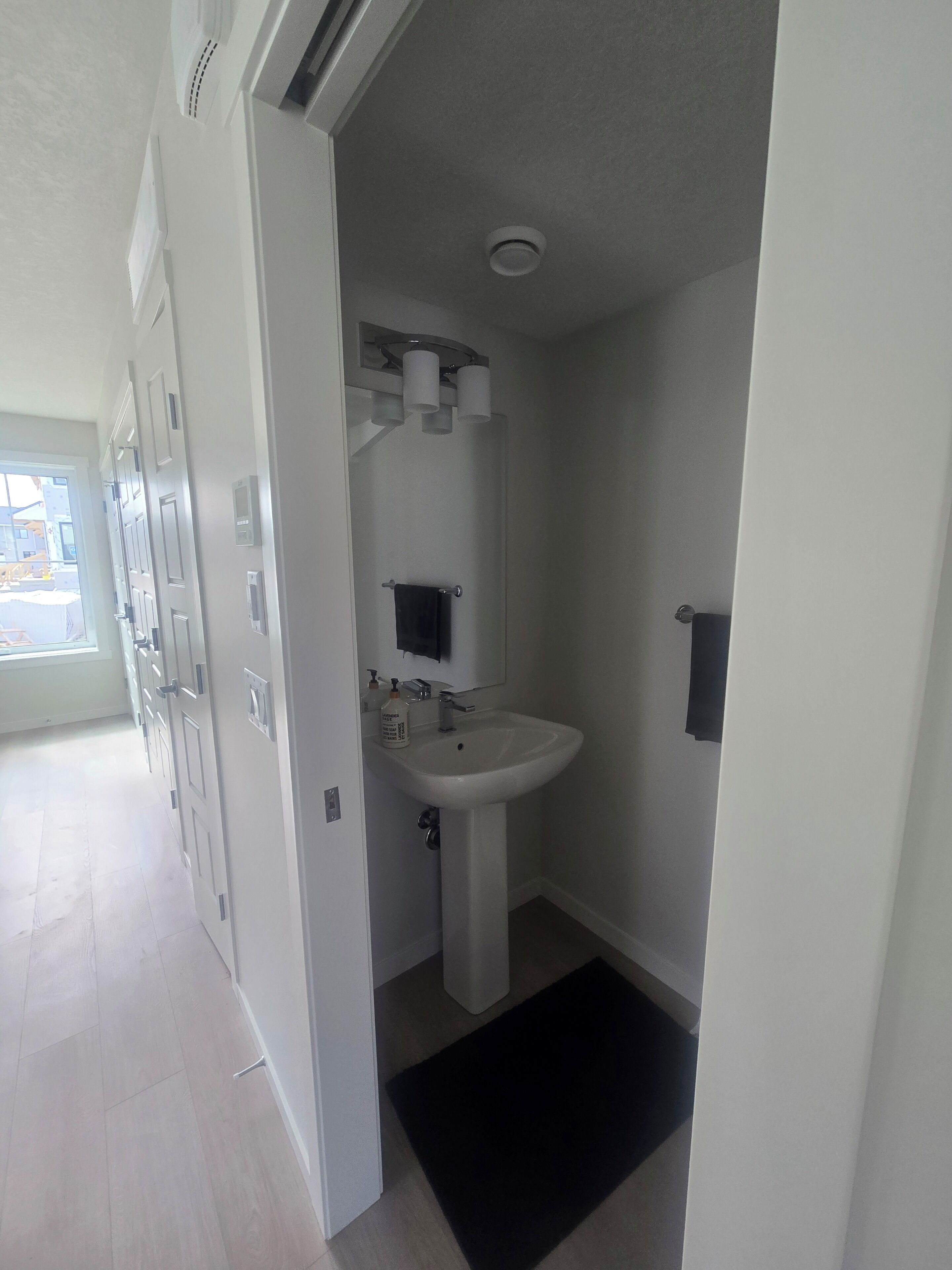 Un baño moderno con lavabo blanco, espejo y toallero.