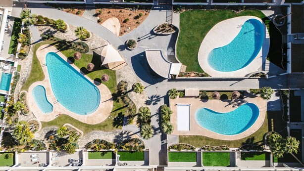 An aerial view of a modern hotel with multiple swimming pools, landscaped areas, and a central courtyard. - Mediterranean Gardens 35: Top floor sea views (Torrevieja)