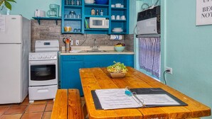 Une cuisine de taille réduite avec des meubles de couleur turquoise, une table en bois et un réfrigérateur blanc.
