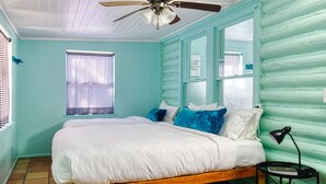 Une chambre à coucher avec un lit en bois, un ventilateur de plafond et une fenêtre avec des stores.