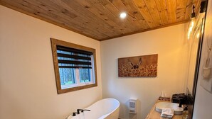 A modern bathroom with a freestanding bathtub, a toilet, and a sink. - Welcome to your haven of peace, a magnificent chalet nestled in the heart of nature. (Rivière-Rouge)